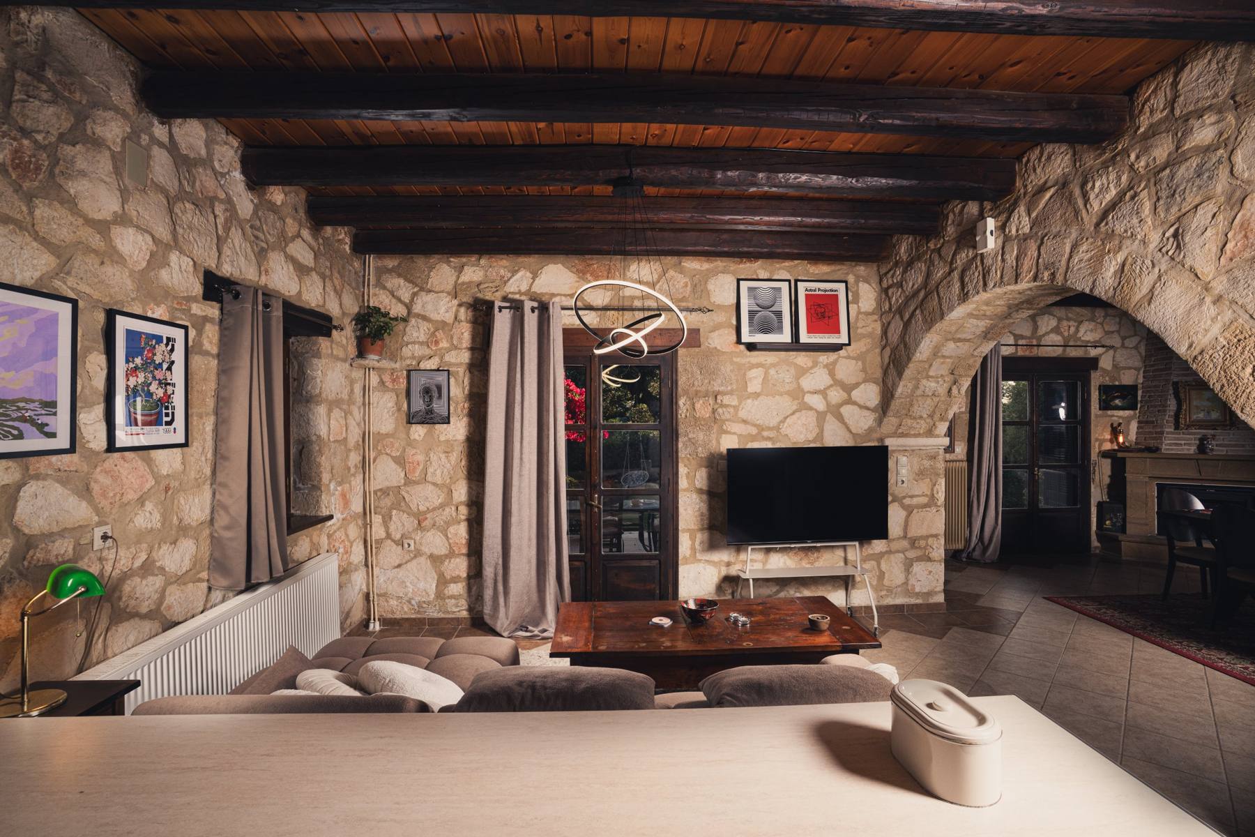 Living room with stone archways and a wall-mounted TV