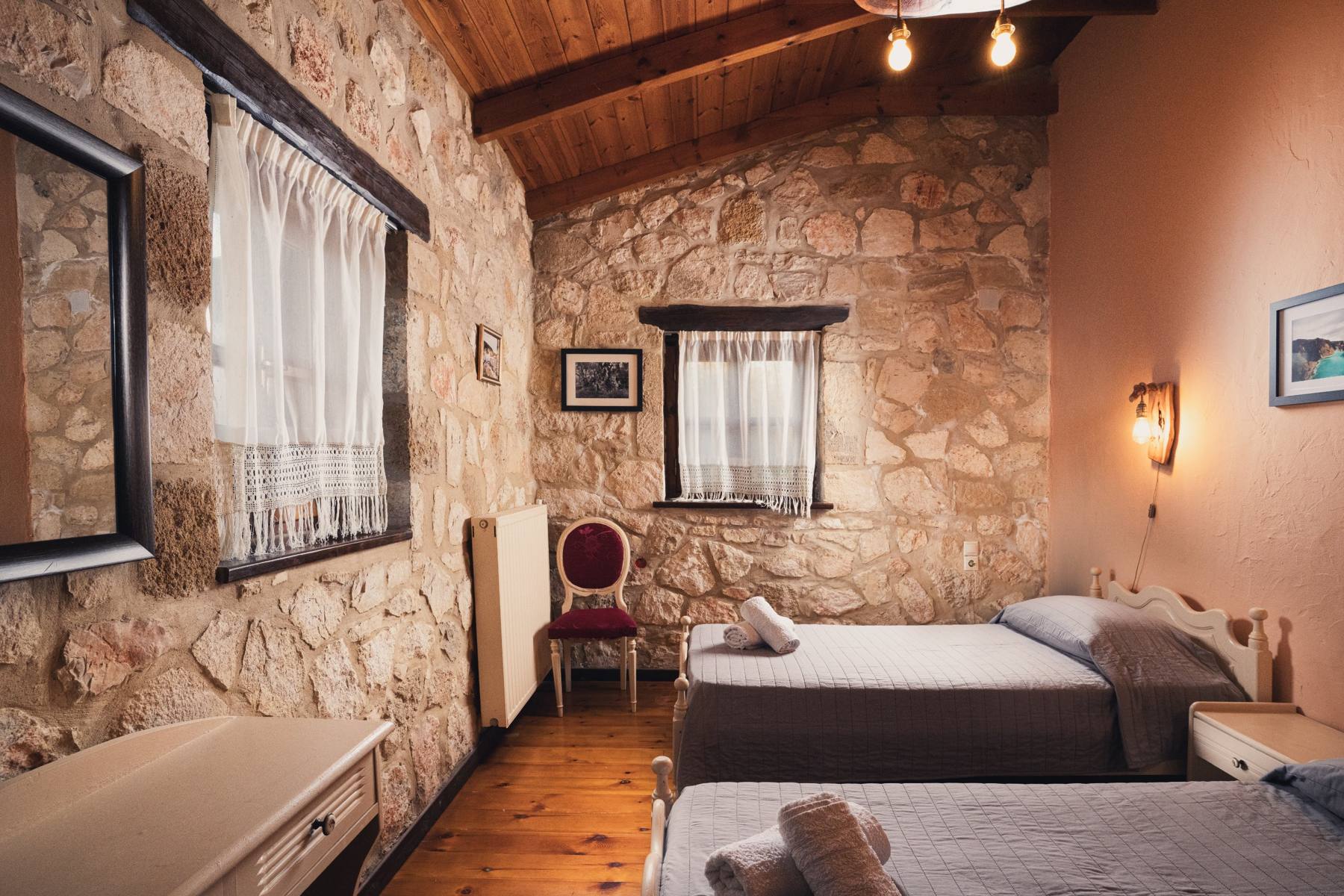 Twin bedroom with stone walls and a red accent chair