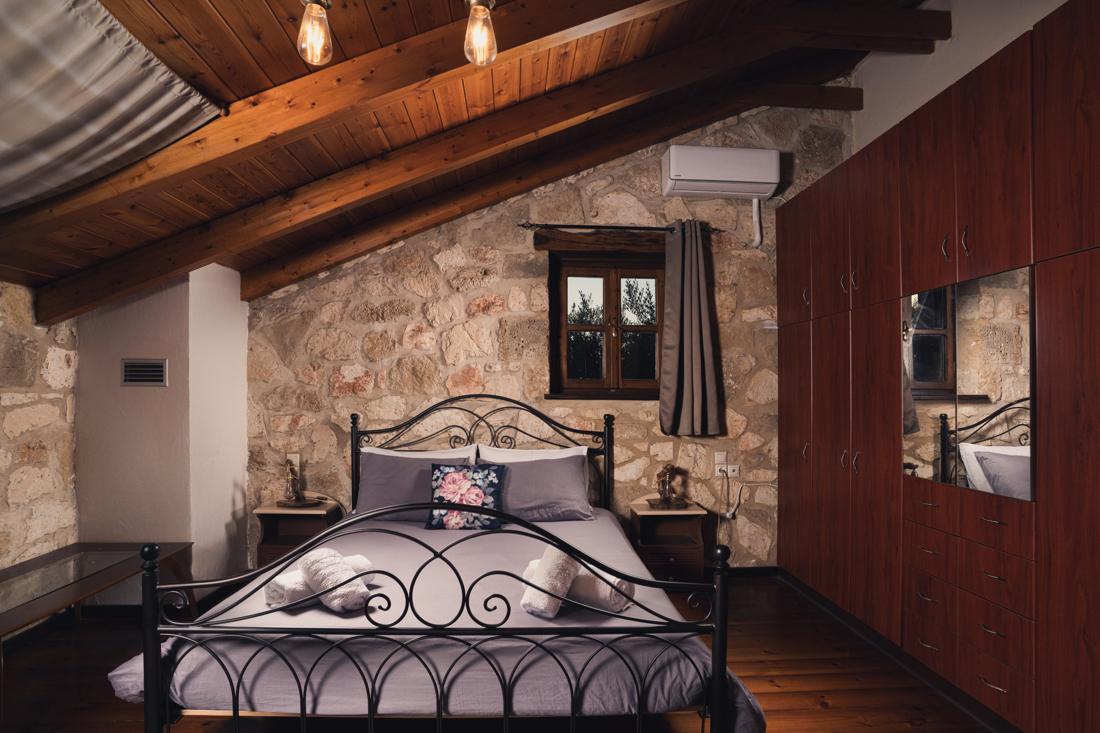 Bedroom with an iron bed and stone walls