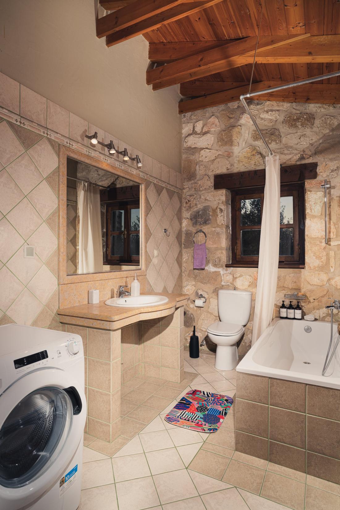 Bathroom with a washing machine and stone wall