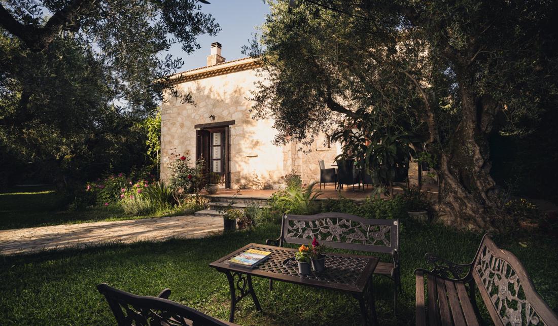 Stone villa seen across the lawn through the olive grove